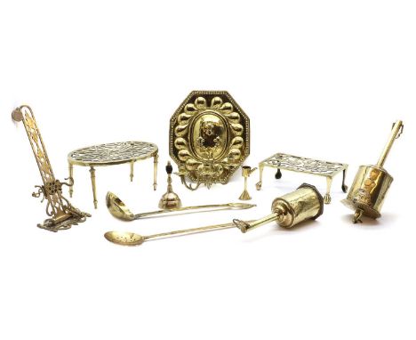 A collection of brassware, Georgian and later, comprising two trivets, the largest 32cm wide, a wall light with embossed fleu