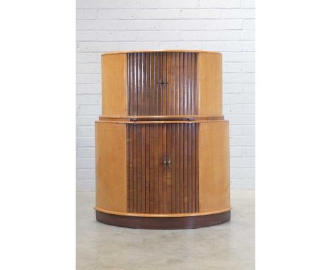 An Art Deco maple and walnut cocktail cabinet, of demilune form, the upper section with a pair of reeded tambour doors openin