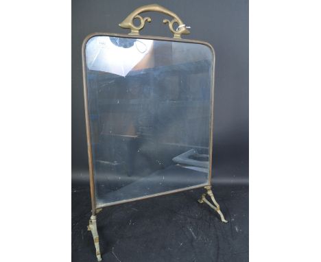 An early 20th century circa. 1910's Art Nouveau gilt metal fireguard having a scrolled handle atop over trestle type base wit