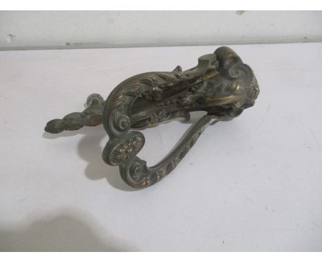 A large brass door knocker decorated with a rams head