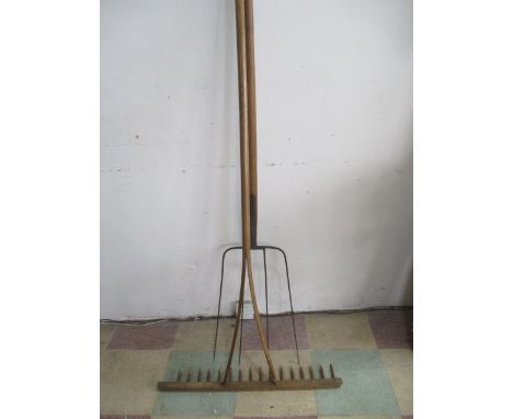 Two large farm tools, a pitchfork along with a rake