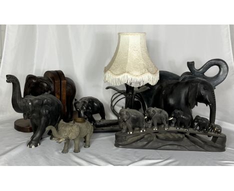 A collection of various elephant figures including a wooden carved lamp with a cobra, elephant bookends etc.