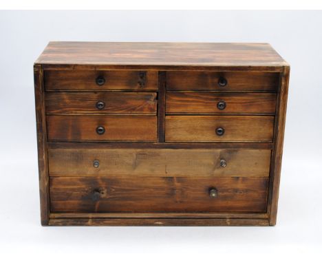 A table-top pine chest of eight drawers, containing various clock parts - length 51cm, depth 23cm, height 36cm