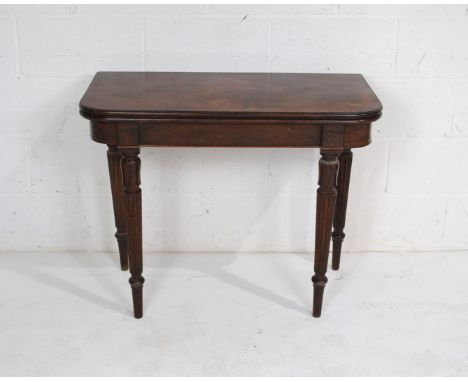 A Georgian mahogany folding card table, with red baize, raised on fluted tapering legs with carved detailing 