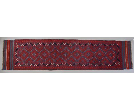 A Meshwani runner of crimson ground &amp; with all-over repeating multi-coloured geometric design, 242cm x 57cm.