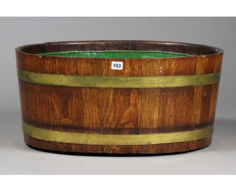 A Lister’s-style coopered oak oval planter with metal liner &amp; brass straps, 62.5cm wide x 29cm high x 47.5cm deep.