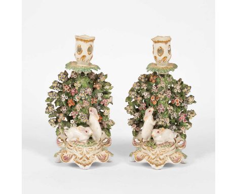 A pair of Derby figural candlesticks, circa 1790, modelled with white rabbits before bocage, the sconce and scroll base highl