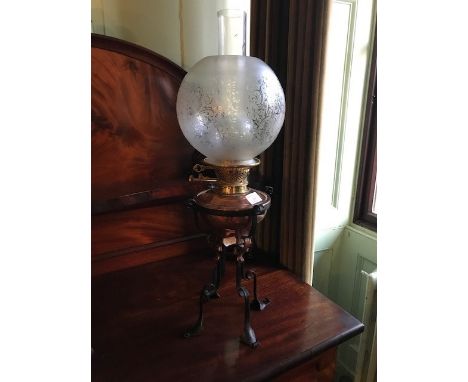 An early 20th century Arts &amp; Crafts copper and iron oil lamp, with globe shaped etched glass shade, 61cms high approx.