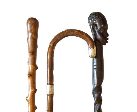 Three early 20th century walking sticks, including ebonised tribal influence stick, light coloured wooden stick and stick wit