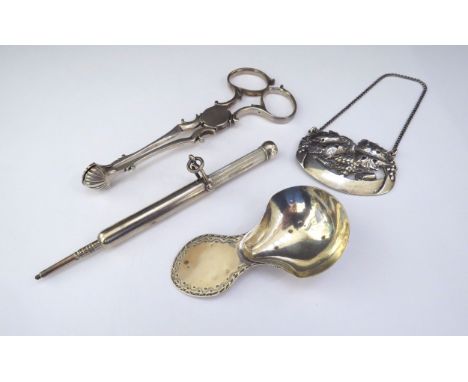 A silver decanter label grape and vine detail, a silver caddy spoon, silver sugar nips and a sterling silver propelling penci