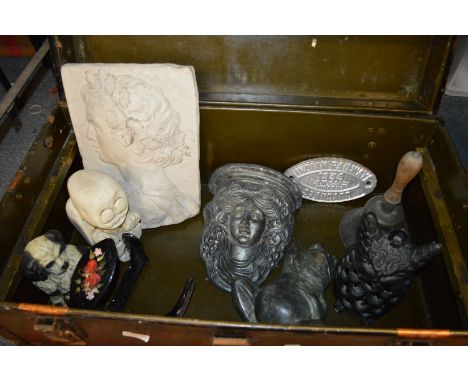 A trunk containing decorative items to include an old hand bell, door stop etc.