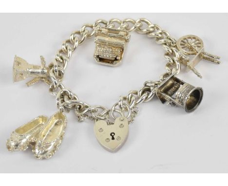 A 925 hallmarked silver charm bracelet, with padlock clasp, the charms including windmill, typewriter, wishing well etc, comb