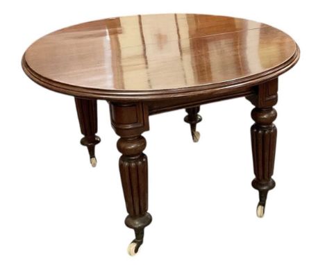 A Victorian mahogany circular extending dining table, with two additional leaves and winding handle, on substantial carved su
