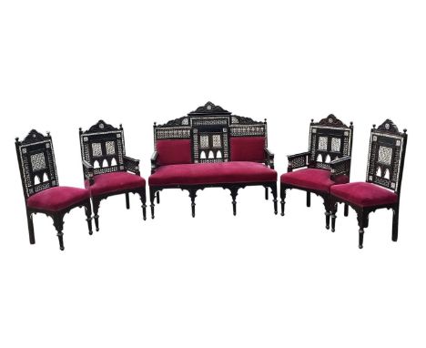 An Eastern mother of pearl and bone inlaid heavily carved five piece salon suite comprising sofa, pair of armchairs and pair 