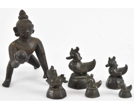 A small Indian bronze figure of crawling Krishna, height 10cm, and a set of five bronze opium weights (6).