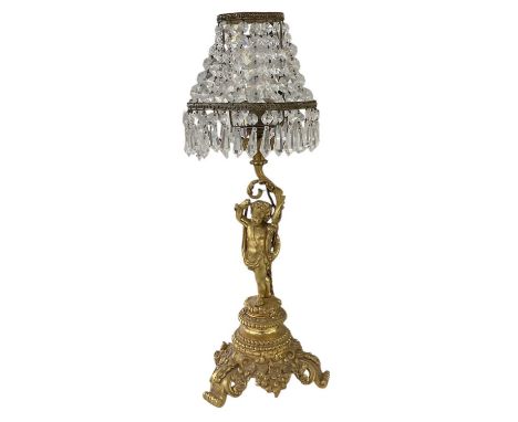 A late 19th/early 20th century French gilt bronze figural table lamp with glass droplet shade, the lamp modelled as a cherub,