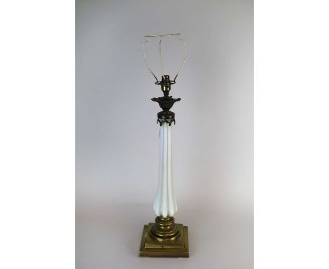 An early 20th century desk lamp, the tapering fluted opaque glass stem below a sconce with cast metal mounts, raised on a ste