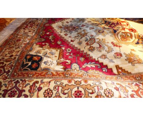 A Heriz style carpet, the medallion on an ivory field with red spandrels surrounded by one frieze and two running borders 230