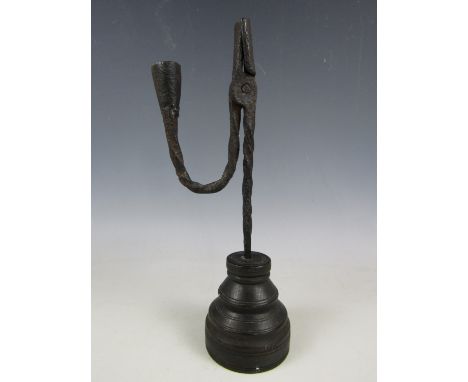 An antique wrought iron rush light, the nip and candle socket raised over a spirally twisted stem and turned wooden base, 30 