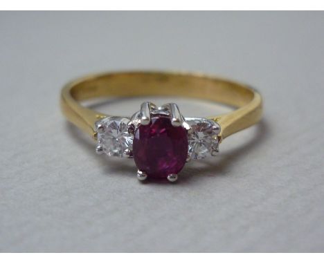 A contemporary three stone ruby and diamond dress ring, the central oval stone of approximately .35ct, crown set above a pair