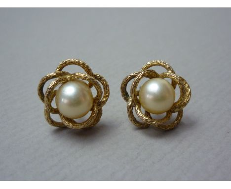 A pair of pearl stud earrings, each set with a central pearl sphere, surrounded by textured wirework petals in 9ct gold