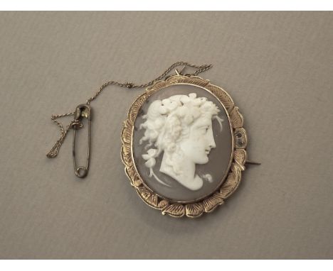 A Victorian shell cameo brooch, carved with the profile portrait of a Maenad with fruiting vines in her hair, rub set in a ye