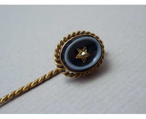 A Victorian diamond and bull's eye agate stick pin, the diamond chip claw and star set to the concave face of a polished agat