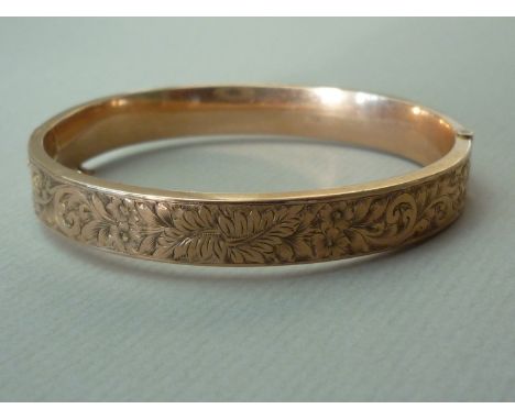 A George V 9ct rose gold hinged bangle, of hexagonal section, decorated with engraved foliate scroll-work, Constantine & Floy