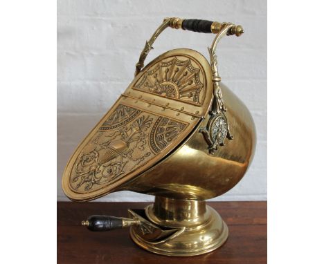 A 19th century brass helmet shaped coal scuttle and shovel, with turned wood handle and embossed detailing, 51cm