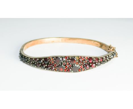 A Victorian fully garnet set, ladies hinged bangle   One garnet missing and clasp needs repair
