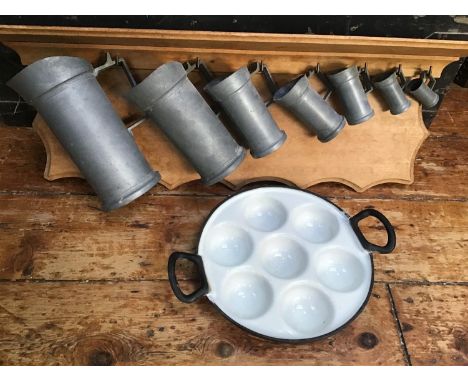 A graduated set of seven pewter apothecary measuring jugs with the measurements on the handle and alphabet numbers to the rim