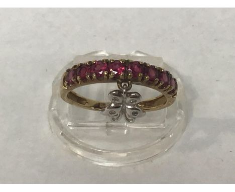 A 9ct gold ring channel set with ruby coloured stones and an attached white metal butterfly charm, ring size O, gross weight 