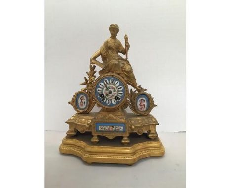 A gilt ormolu figural mantel clock surmounted with a lady holding a torch reading a book, porcelain dial with central floral 