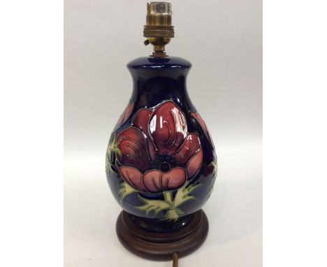 A Moorcroft Pottery table lamp, of ovoid form with flared rim, decorated in the Clematis pattern to a blue ground, on wooden 