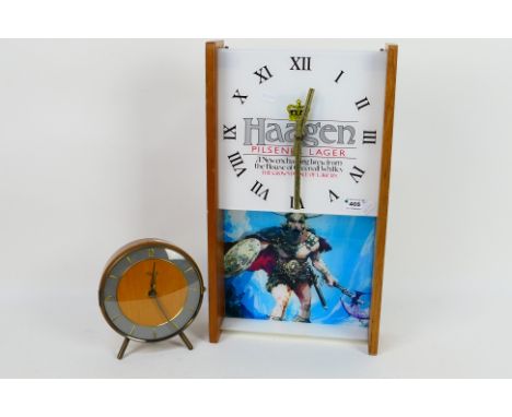 A Greenall Whitley Haagen Pilsner Lager advertising wall clock and one other. [2]. [W]
