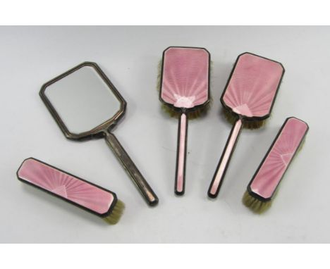 A George VI silver and pink guilloche enamel dressing table set, comprising hand mirror, pair of hair brushes and a pair of c