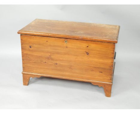 A pine trunk, with cast iron carrying handles, raised on bracket feet, 95cm x 58.5cm x 61.5cm.