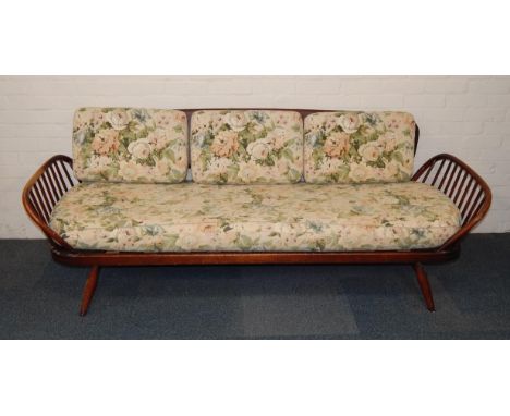 An Ercol oak day bed, with spindle sides, floral upholstered cushion, and detachable back, raised on splayed legs, 209cm long