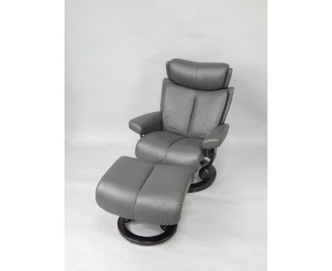 An EXO Stressless Magic large black leather armchair, on a circular wooden swivel base, together with a matching foot stool.