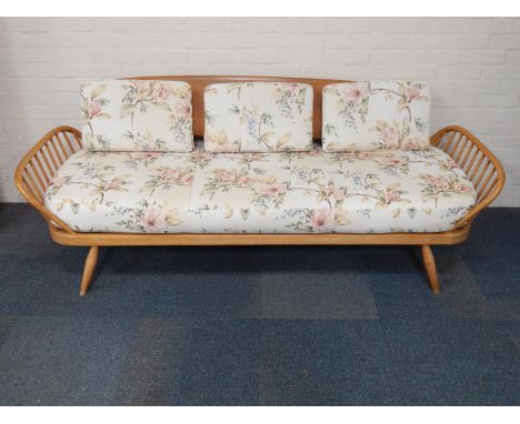 An Ercol beech and elm day bed sofa, with removable back, floral upholstered loose cushions, raised on splayed legs, 207cm lo