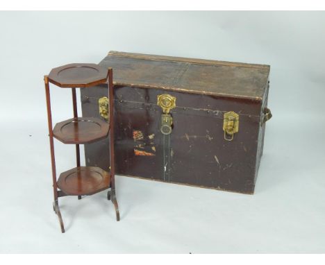 An Edwardian mahogany three tier folding cake stand, 70cm high, and a cabin trunk bearing traces of labels, 86.5cm x 43.5cm x