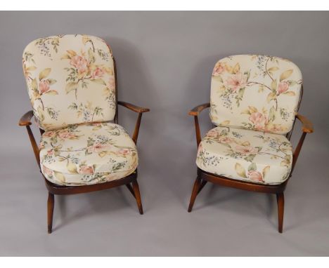 A pair of Ercol oak spindle back armchairs, with floral upholstered loose cushions, raised on turned legs united by stretcher