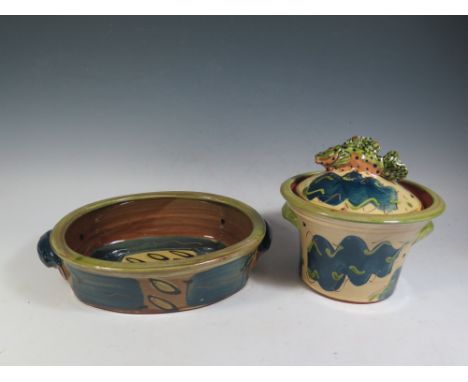 A Josie Walter Pot with cover decorated with a fish finial, 21.5cm diam. and a similar baking dish