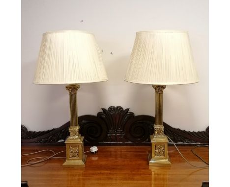 A pair of brass column lamp bases with silk shades total height 82cm x base 14cm x 14cm 