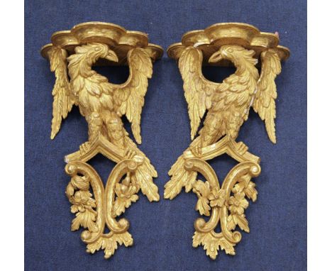 A pair of 18th century carved giltwood wall brackets, each modelled as an eagle with outstretched wings with serpentine shelf