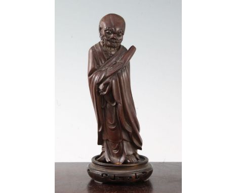 A Chinese hardwood figure of Luohan, 19th century, holding a scroll in both hands standing and wearing flowing robes, his rib