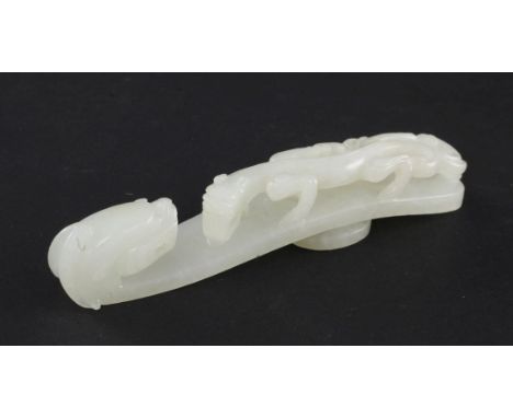 A Chinese white jade 'dragon' belt hook, 18th / 19th century, the handle carved in high relief and openwork with a chi dragon