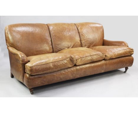 A brown leather three seater sofa, with rounded arms, on tapering turned legs and castor feet