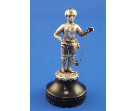 A continental silver miniature figure of a negro playing diablo, on base with Greek key border and wooden plinth, unmarked, o