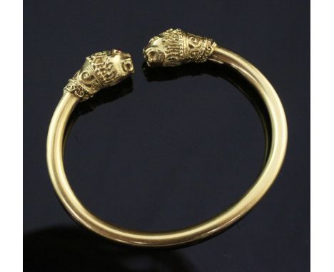 An 18ct gold open bangle, with leopard's head terminals and gem set eyes, gross weight 22 grams.